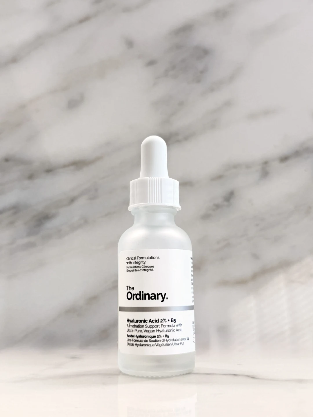 The Ordinary Hyaluronic Acid 2% + B5 serum bottle photographed against a marble background.