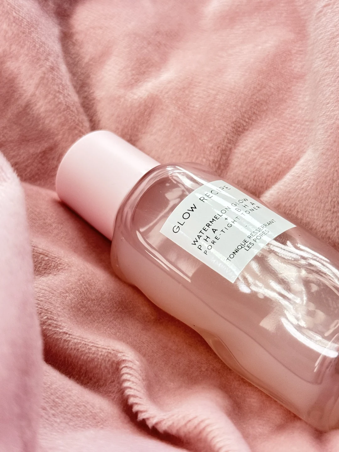Glow Recipe Watermelon Glow PHA + BHA toner styled on soft pink fabric.